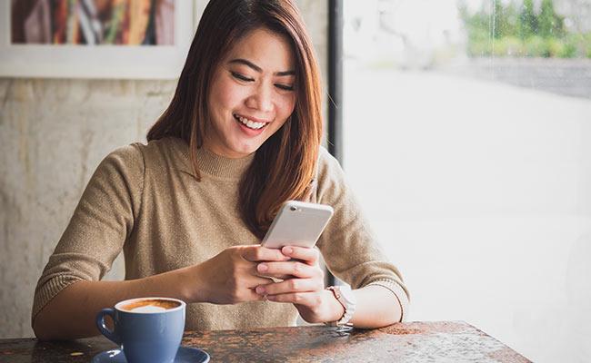 Woman smiling while texting on her phone
